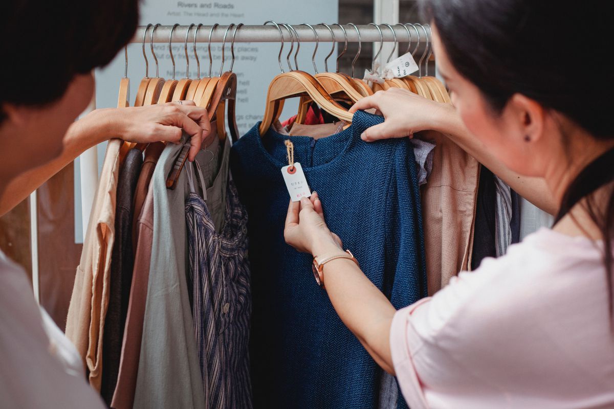 Zwei Frauen sehen sich die Info zu T-Shirts an einem Ständer an.